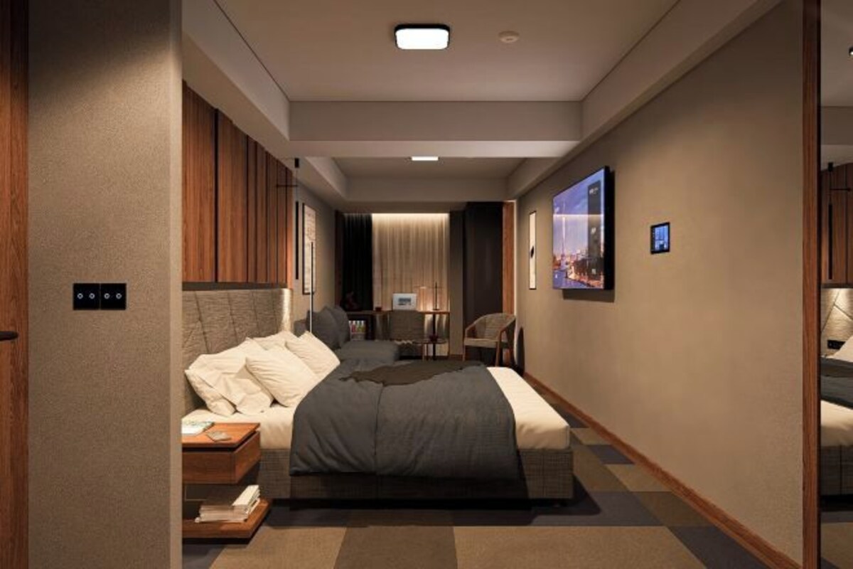 A modern hotel room with a large bed, a desk, and a chair.