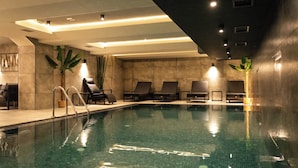 An indoor swimming pool with lounge chairs and potted plants. - Lumière Hotel (Belgrade)