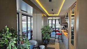 A modern hotel lobby with a bar, seating area, and large windows offering views of the city. - Lumière Hotel (Belgrade)