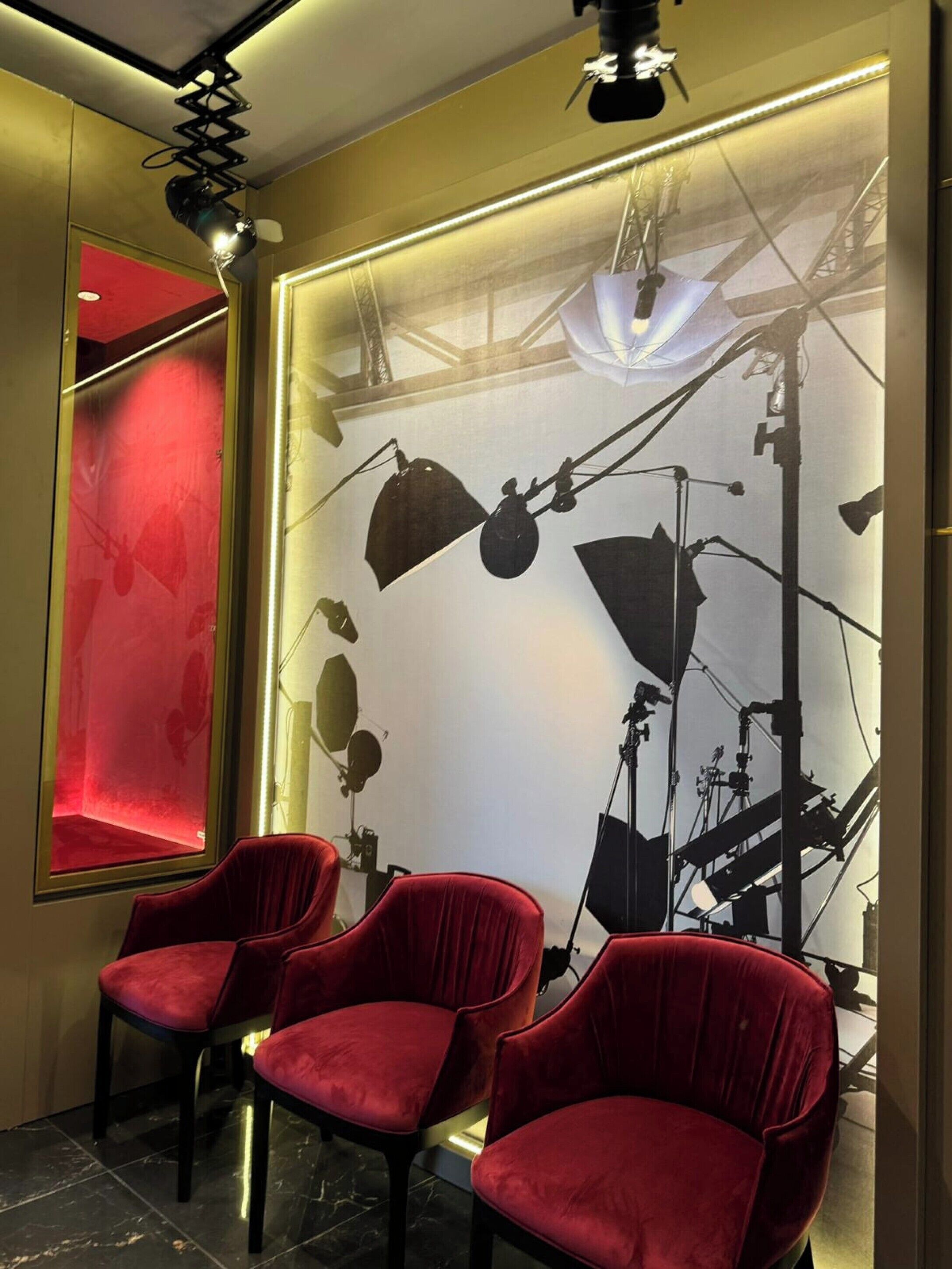 A room with a red velvet chair, a red accent wall, and a large window with a view of a bridge.