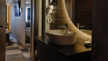A modern bathroom with a large curved mirror, a sink, and a toilet paper holder.