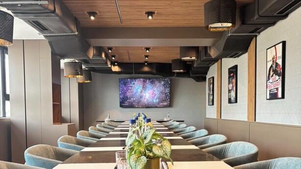 A modern conference room with a large table, blue upholstered chairs, and a television screen on the wall. - Lumière Hotel (Belgrade)