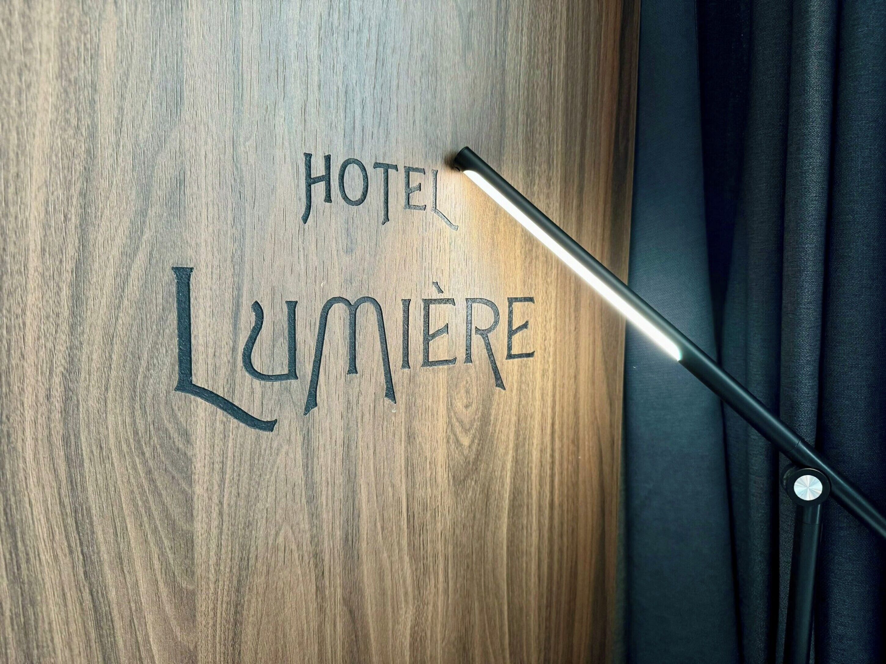 A wooden surface with the words "HOTEL LUMIERE" engraved.