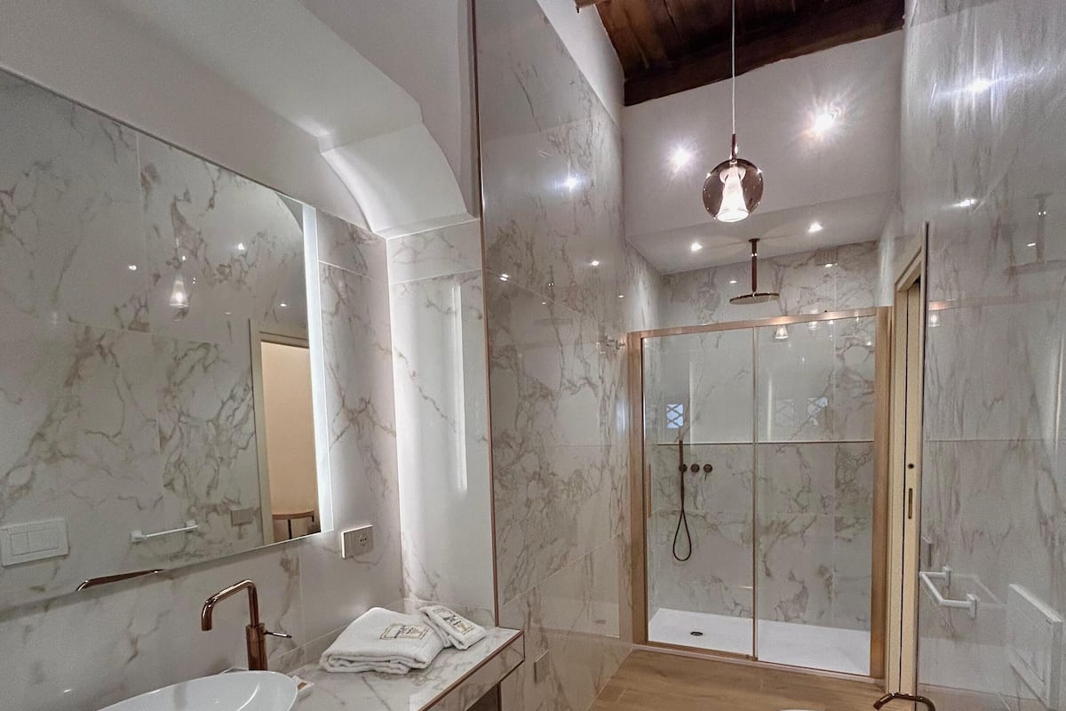 Une salle de bain moderne avec deux vasques, une douche en verre et des murs en marbre.