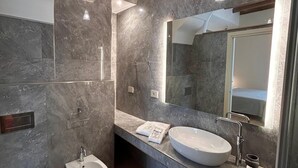 A modern bathroom with a large mirror, a vessel sink, a bidet, and a wooden ceiling. - Heraklean Suites Tropea (Tropea)