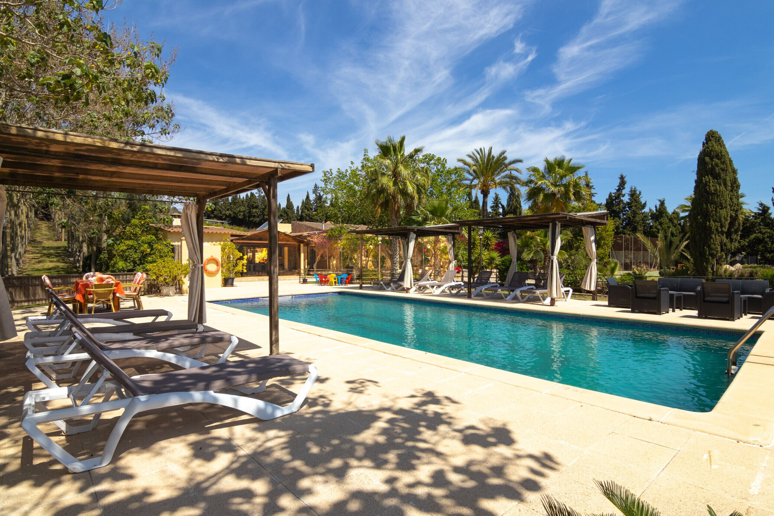 Une piscine avec des chaises longues et une pergola.