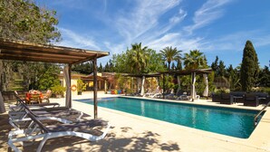 Una piscina con sillas de descanso y una pérgola.