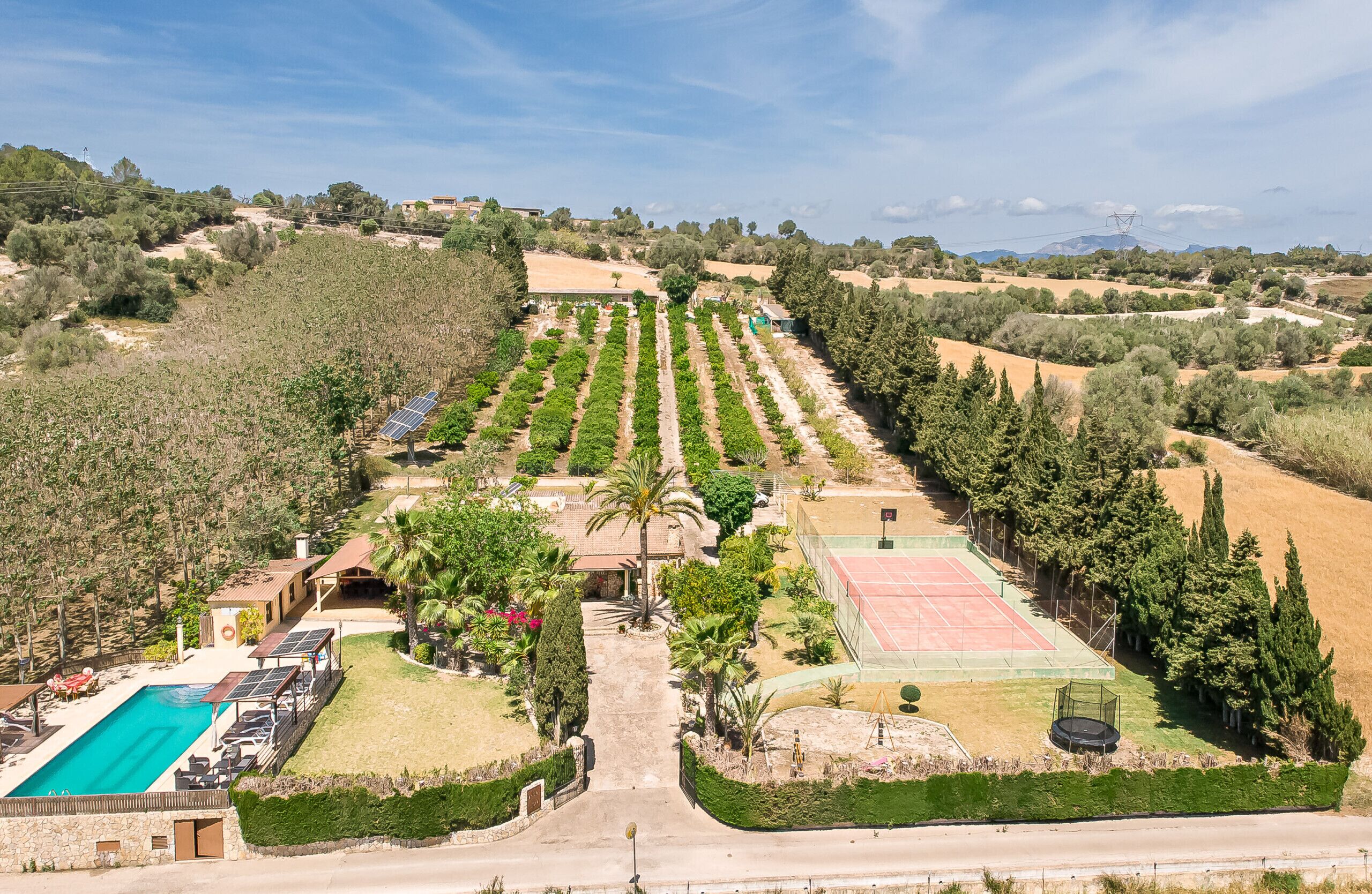 A large property with a swimming pool, tennis court, and solar panels.