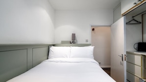 A neatly arranged bedroom with a bed, bedside table, and a wardrobe.