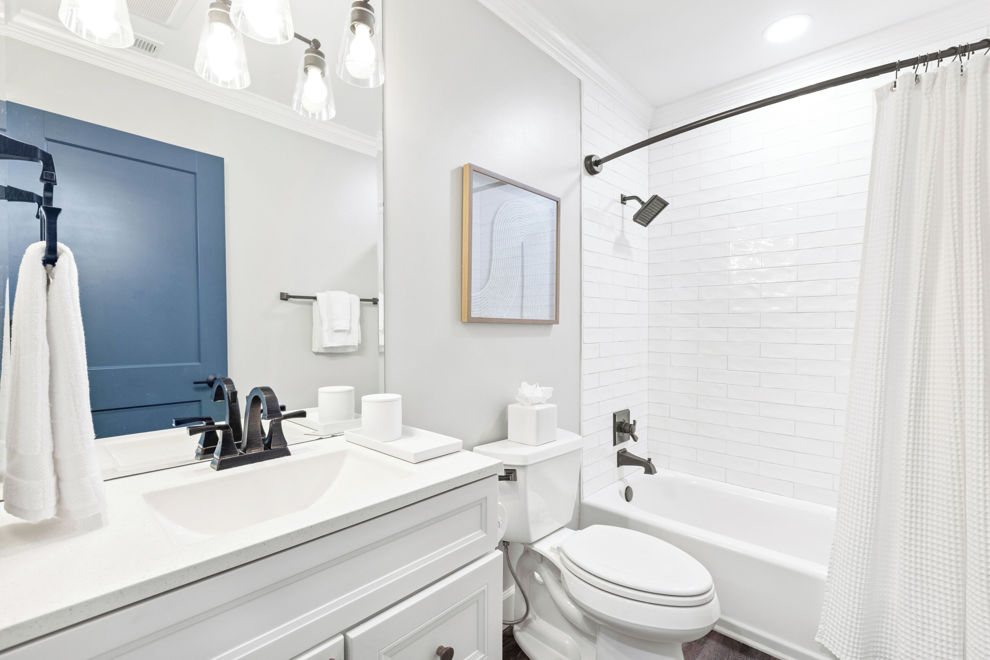 A modern bathroom with a white sink, black faucet, and a blue door.