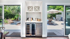 A modern kitchen with a built-in island, glass doors leading to a patio, and outdoor seating area. - 60 Lawton Rd: Sea Pines (Hilton Head)