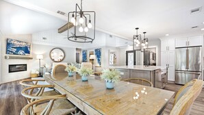 A spacious kitchen with a large island, modern appliances, and a dining area with a glass table and wooden chairs. - 60 Lawton Rd: Sea Pines (Hilton Head)