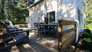 Une terrasse en bois, aménagée avec du mobilier d’extérieur, notamment des chaises et des tables, et un espace abrité comprenant une table et des chaises.