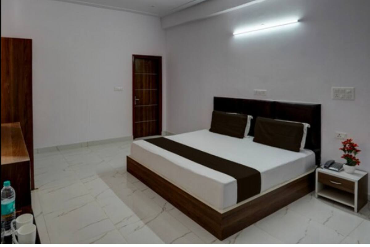A modern bedroom with a large bed, a bedside table, a nightstand, and a wardrobe.