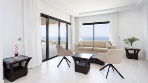 A modern living room with a sofa, two armchairs, a glass coffee table, and a side table with a plant.