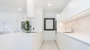 A modern kitchen with white cabinetry, a central island, and a marble backsplash.