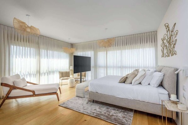 Un dormitorio moderno con una cama grande, un sofá, un televisor y un adorno en la pared.