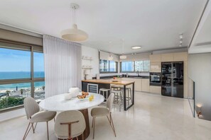 Una cocina moderna con una isla grande, un comedor con mesa redonda y vistas al océano.