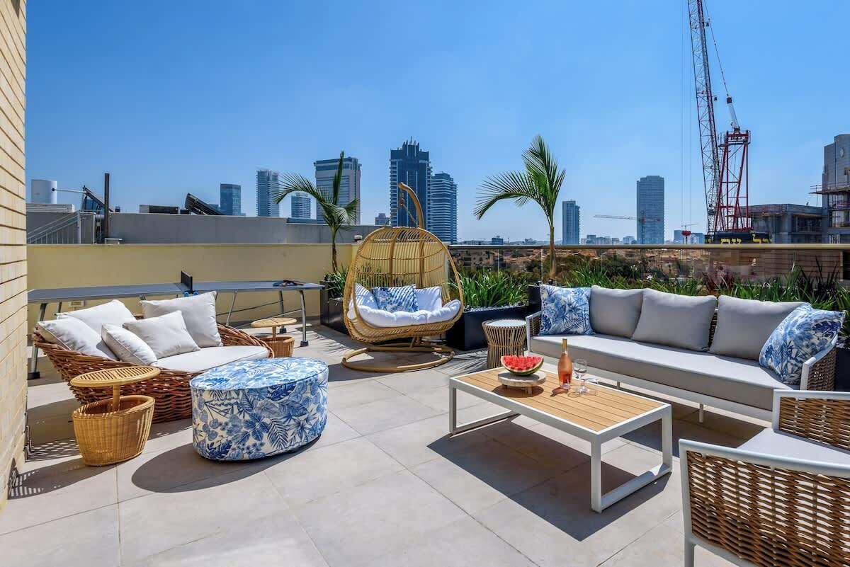 Una terraza en la azotea con mobiliario exterior, incluyendo un sofá, sillas y una mesa.