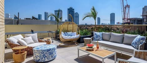 Una terraza en la azotea con mobiliario exterior, incluyendo un sofá, sillas y una mesa.