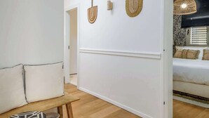 A modern interior with a wooden floor, a white sofa, a small round table, and a bed with a patterned headboard. - #Breathtaking 4BR/3BA Duplex Seafront (Tel Aviv-Yafo)