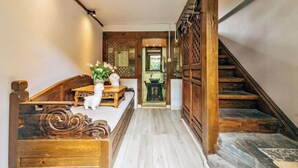 A wooden staircase leading to a room with a bed, a small table with a cat figurine, and a decorative wall.