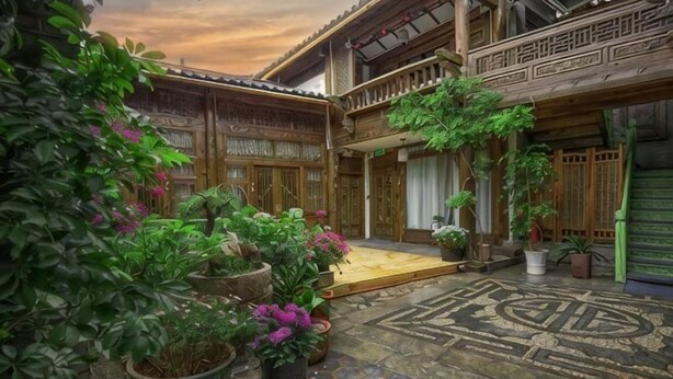 A courtyard with potted plants, a tiled floor, and traditional wooden architecture.