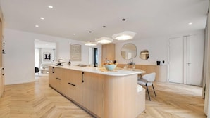 Een moderne keuken met een centraal kookeiland, houten kastjes en een visgraatvloer.