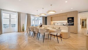 Een moderne keuken met een centraal eiland, houten kastjes en hangende lampen.