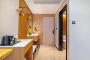 A modern bathroom with a wooden vanity, a mirror, a towel rack, and a toilet visible through an open door. - Jinhua Mantingxuan Hotel (Zhejiang Normal University) (Jinhua)