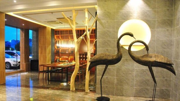 A lobby with a polished marble floor, a dining area with tables and chairs, and two large bird sculptures on pedestals. - Jinhua Mantingxuan Hotel (Zhejiang Normal University) (Jinhua)