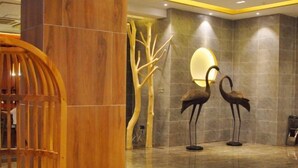 A lobby with a wooden reception desk, a decorative tree sculpture, and two bird sculptures on the floor. - Jinhua Mantingxuan Hotel (Zhejiang Normal University) (Jinhua)