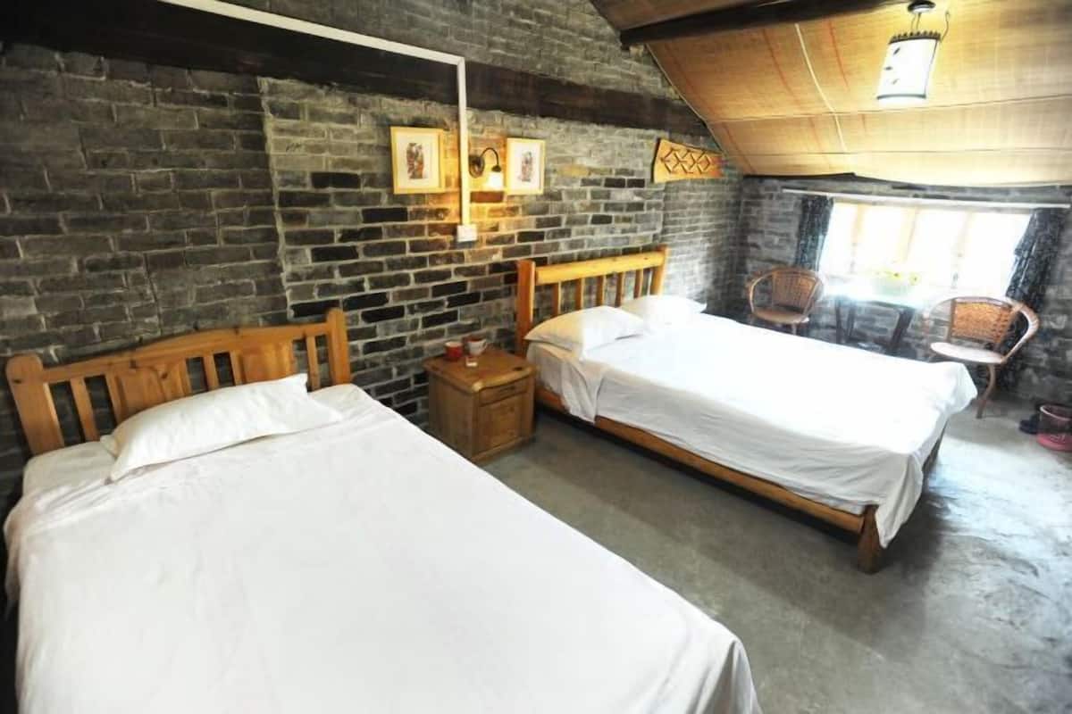 A room with two wooden beds, a brick wall, and a small table with chairs.