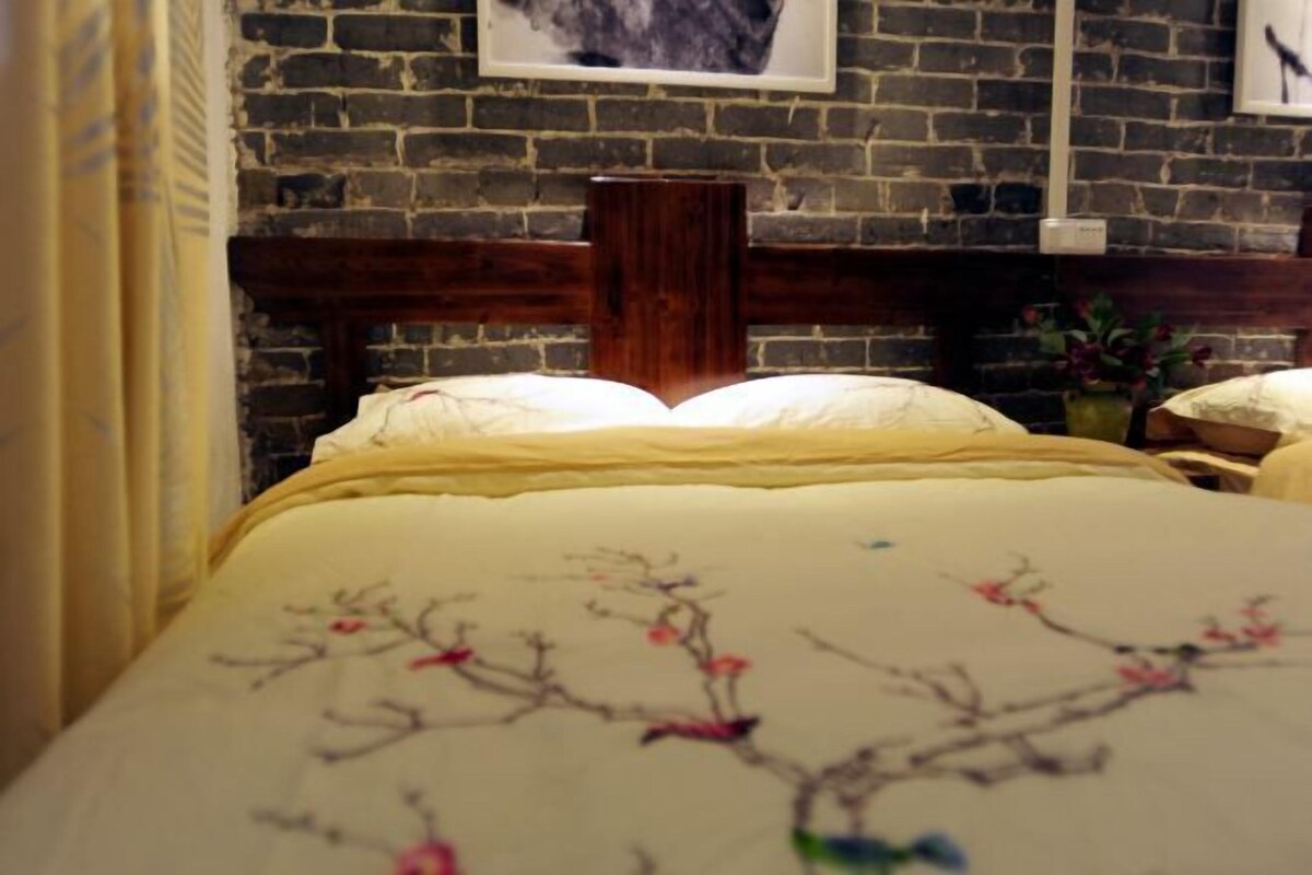 A bed with a wooden headboard, a brick wall, and a framed picture above the bed.