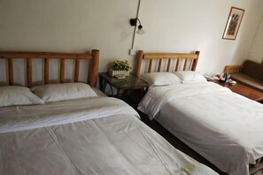 A room with two single beds, a small table with a vase of flowers, a wall-mounted lamp, and a framed picture. - Huangyao Guyaju Farm Inn (Zhaoping)