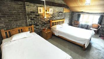 A rustic room with two wooden beds, a brick wall, and a small table with chairs.