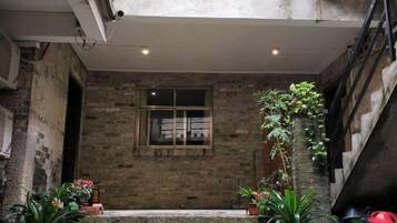 A stone staircase leading to a door with a window, surrounded by potted plants.