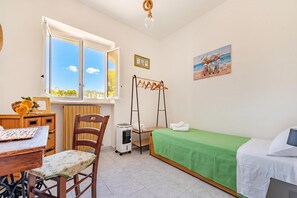 A room with a bed, a table with a chair, a window with a view, a drying rack, and a painting on the wall. - Casa Vacanze Minare Selva di Fasano (Fasano)
