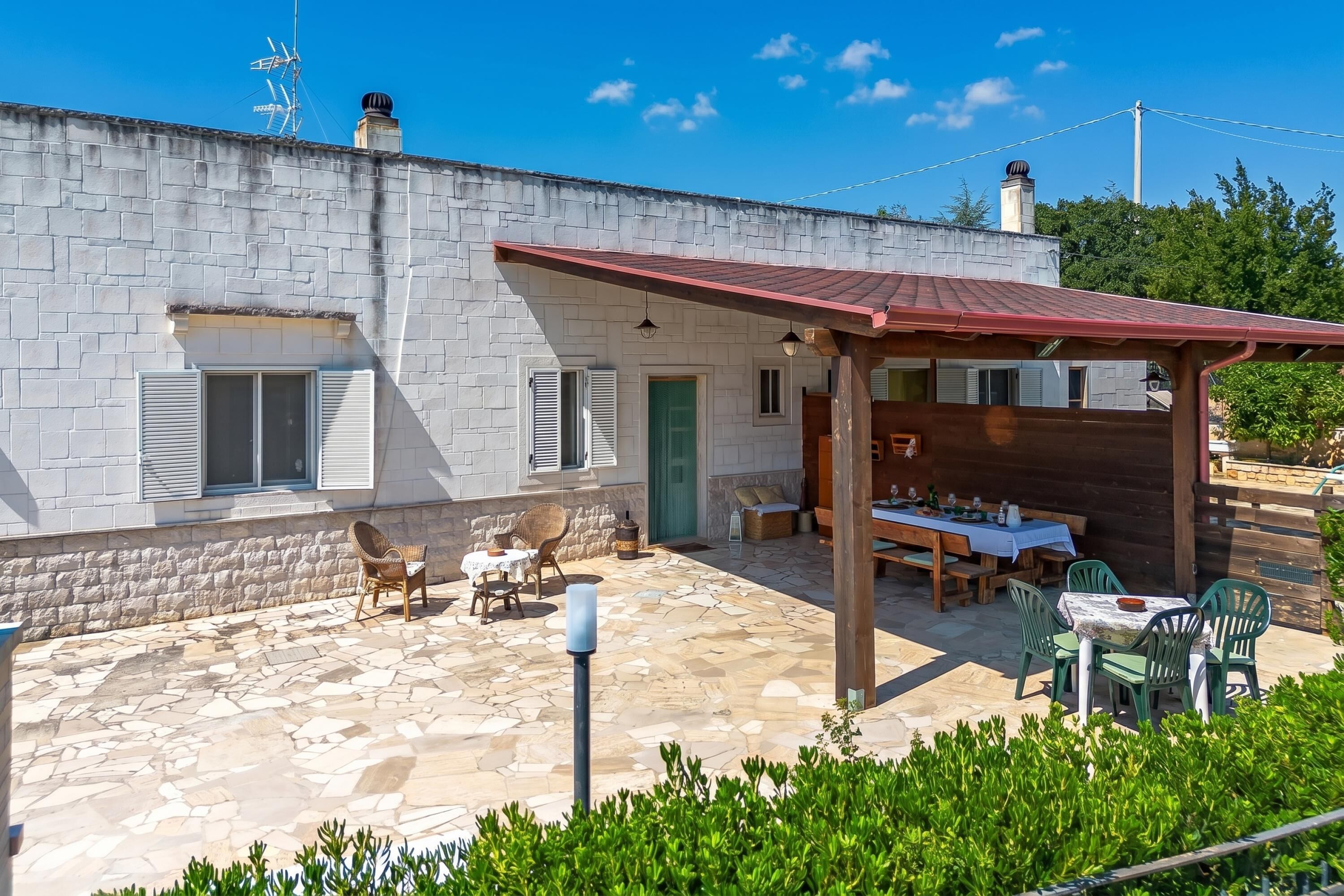 Un edificio de piedra con un patio amueblado y una pérgola de madera.