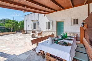 An outdoor dining area with a table set for four, benches, and a brick building in the background. - Casa Vacanze Minare Selva di Fasano (Fasano)
