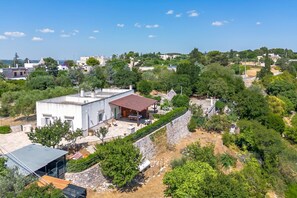 A modern house with a large patio, a covered outdoor area, and a stone retaining wall. - Casa Vacanze Minare Selva di Fasano (Fasano)