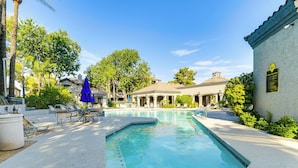 A swimming pool with lounge chairs and umbrellas, surrounded by trees and buildings. - 3 Mi to Tpc: Chic Condo w/ Pool Access & Grills (Scottsdale)