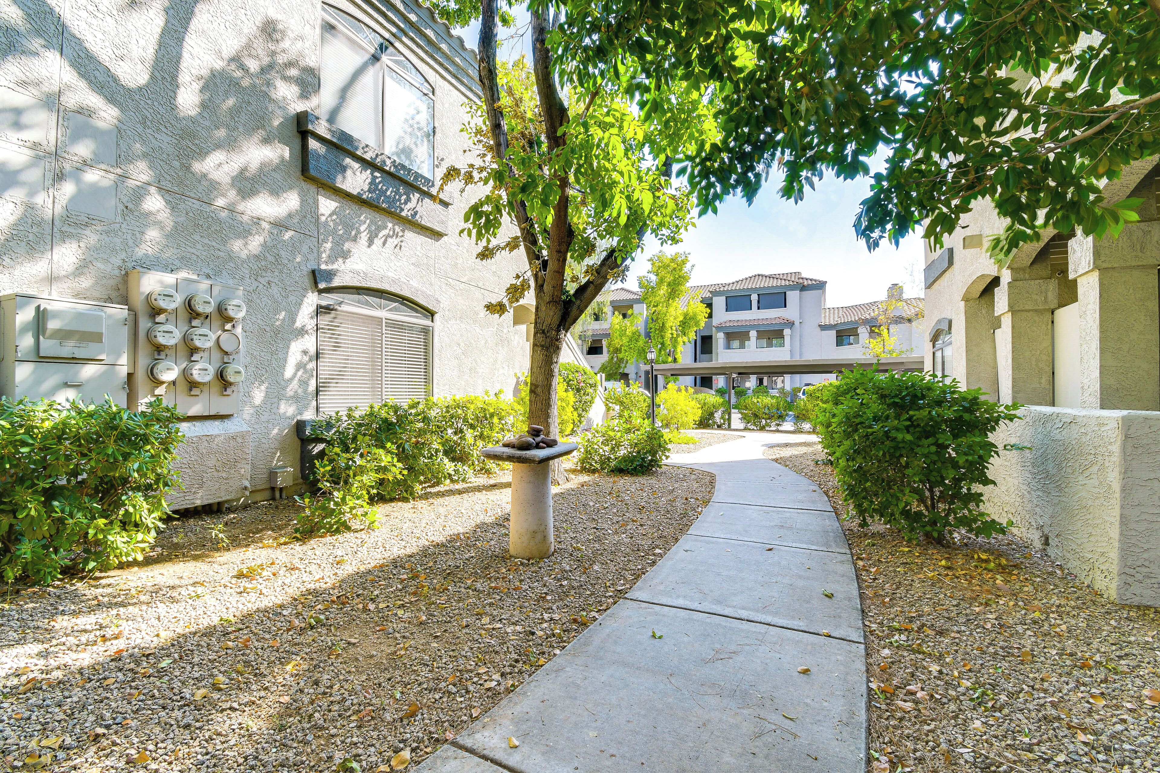 A pathway leading to a building with a stone pillar and a row of windows.