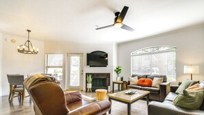 A living room with leather sofas, a coffee table, a fireplace, a TV mounted above it, and a ceiling fan. - 3 Mi to Tpc: Chic Condo w/ Pool Access & Grills (Scottsdale)
