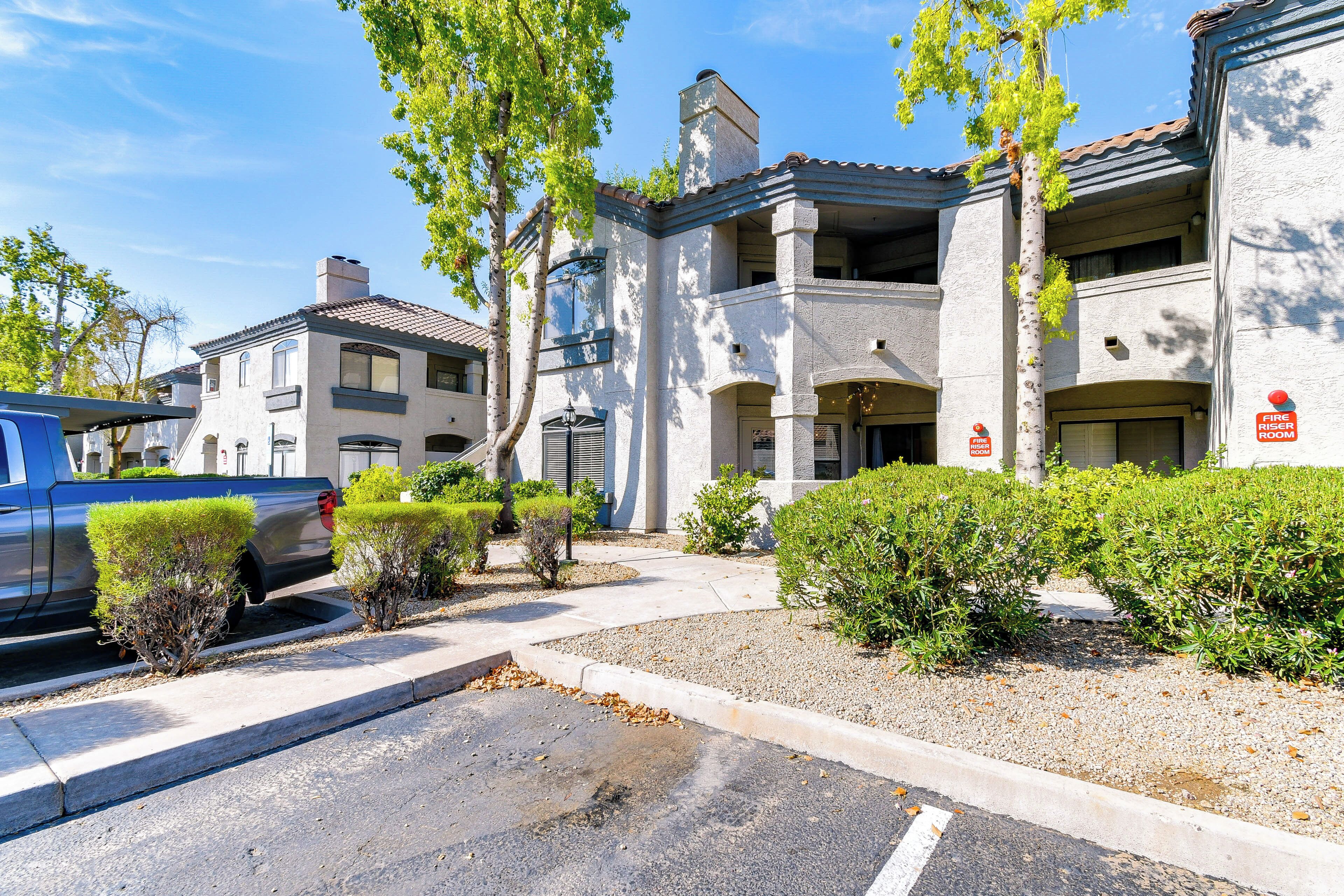 A multi-story building with a fire escape, a parking area, and a driveway.