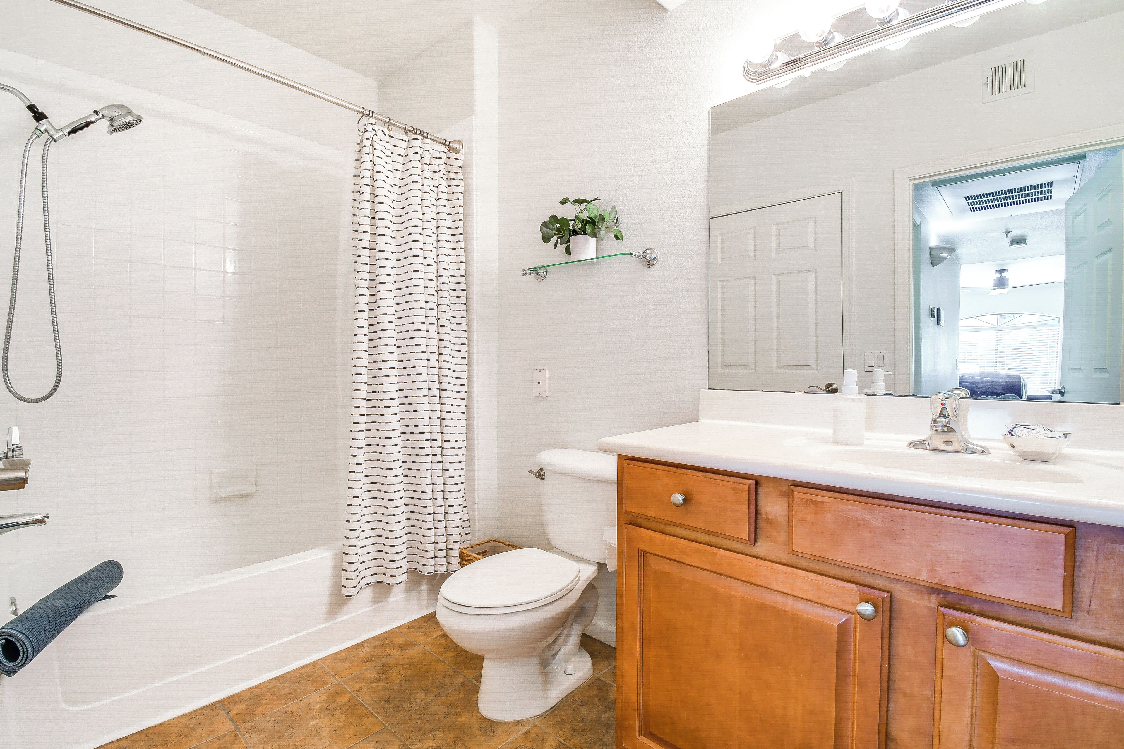 A bathroom with a bathtub, toilet, and vanity with a mirror.