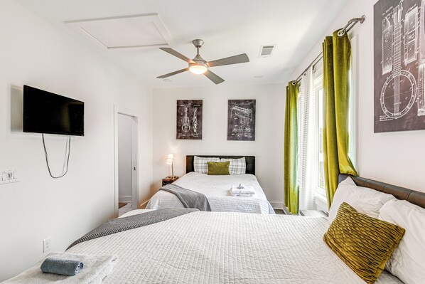 A hotel room with two beds, a ceiling fan, a flat-screen TV, and artwork on the walls. - Bright Nashville Townhome ~ 5 Mi to Downtown! (Nashville)