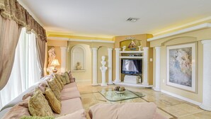 A living room with a sofa, television, and decorative items. - Pompano Beach Home w/ Pool & Dock ~ 4 Mi to Pier! (Pompano Beach)