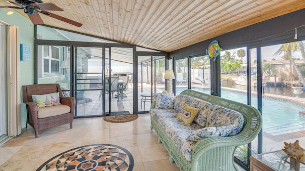 A spacious indoor area with a ceiling fan, wicker furniture, a pool view, and a dining area. - Pompano Beach Home w/ Pool & Dock ~ 4 Mi to Pier! (Pompano Beach)
