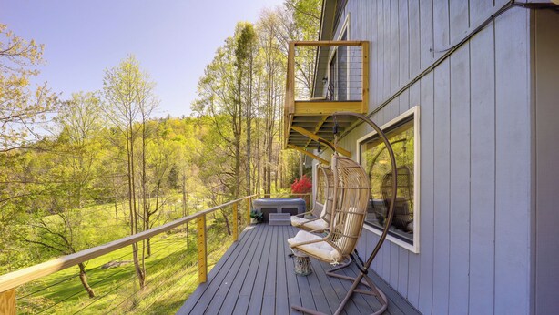 A wooden deck with a railing, a wicker chair, and a small table. - 24 Private Acres: Trails/hot Tub Near Blowing Rock (Lenoir)